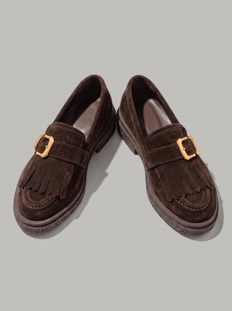 Lecce Dark Brown - מוקסין זמש בחום כהה עם פרנזים בחזית, רצועת אבזם מוזהבת ותפר מוקסין סביב החרטום. הסוליה בעלת טקסטורה בולטת.