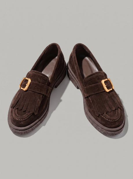 Lecce Dark Brown - מוקסין זמש בחום כהה עם פרנזים בחזית, רצועת אבזם מוזהבת ותפר מוקסין סביב החרטום. הסוליה בעלת טקסטורה בולטת.