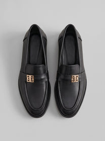 Volterra Black - מוקסין עור שחור עם רצועה רחבה בחזית ועיטור מתכתי זהוב, תפר מודגש סביב החרטום וסוליה דקה.