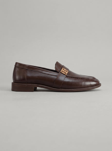 Volterra Dark Brown - מוקסין עור בחום כהה עם רצועה רחבה בחזית ועיטור מתכתי זהוב, תפר מודגש סביב החרטום וסוליה דקה.