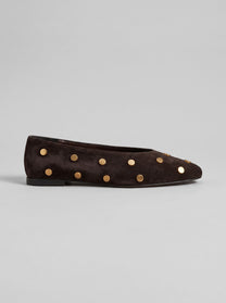 Aurelia Chocolate Brown - נעל בלרינה מזמש בחום שוקולד עם חרטום מעוגל ועיטורי ניטים עגולים בגוון זהב על הגפה.