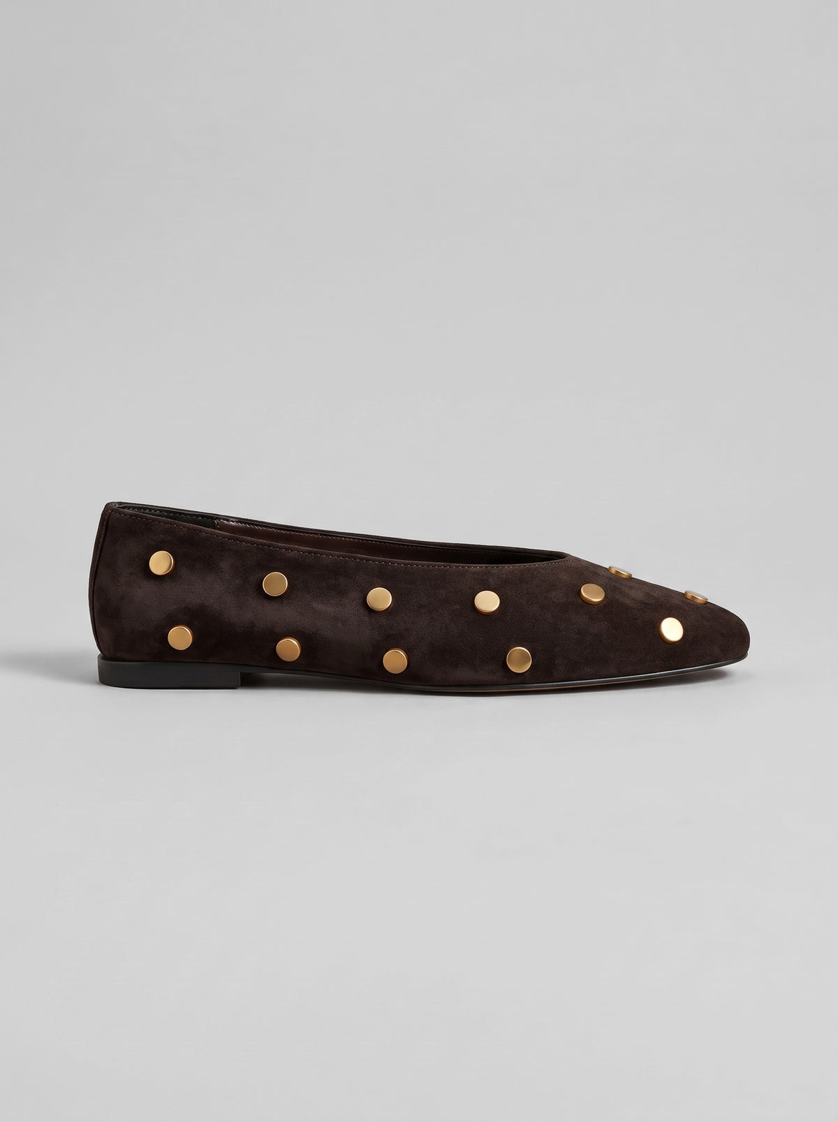 Aurelia Chocolate Brown - נעל בלרינה מזמש בחום שוקולד עם חרטום מעוגל ועיטורי ניטים עגולים בגוון זהב על הגפה.