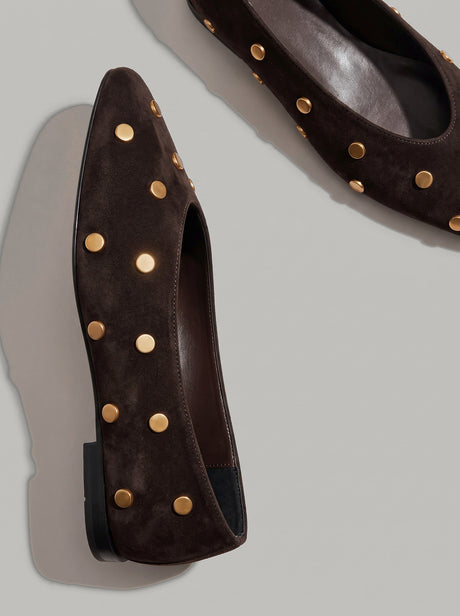 Aurelia Chocolate Brown - נעל בלרינה מזמש בחום שוקולד עם חרטום מעוגל ועיטורי ניטים עגולים בגוון זהב על הגפה.