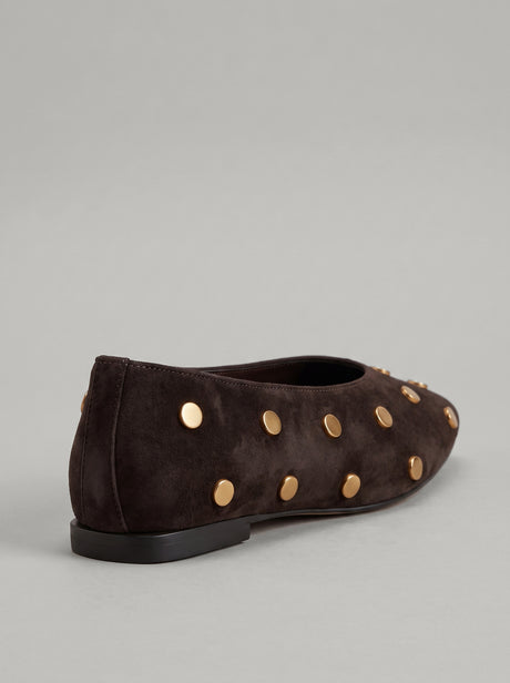 Aurelia Chocolate Brown - נעל בלרינה מזמש בחום שוקולד עם חרטום מעוגל ועיטורי ניטים עגולים בגוון זהב על הגפה.