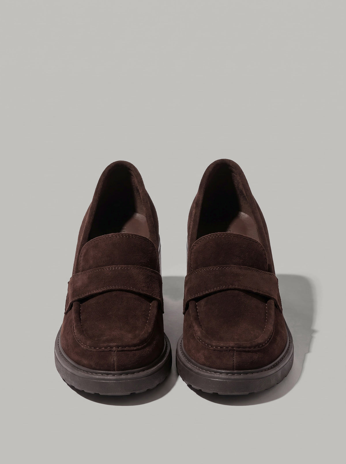 Positano Dark Brown - מוקסין זמש בחום כהה עם רצועה רחבה על החזית, תפר מודגש סביב החרטום, עקב בלוק וסוליה בעלת מראה מחורץ.